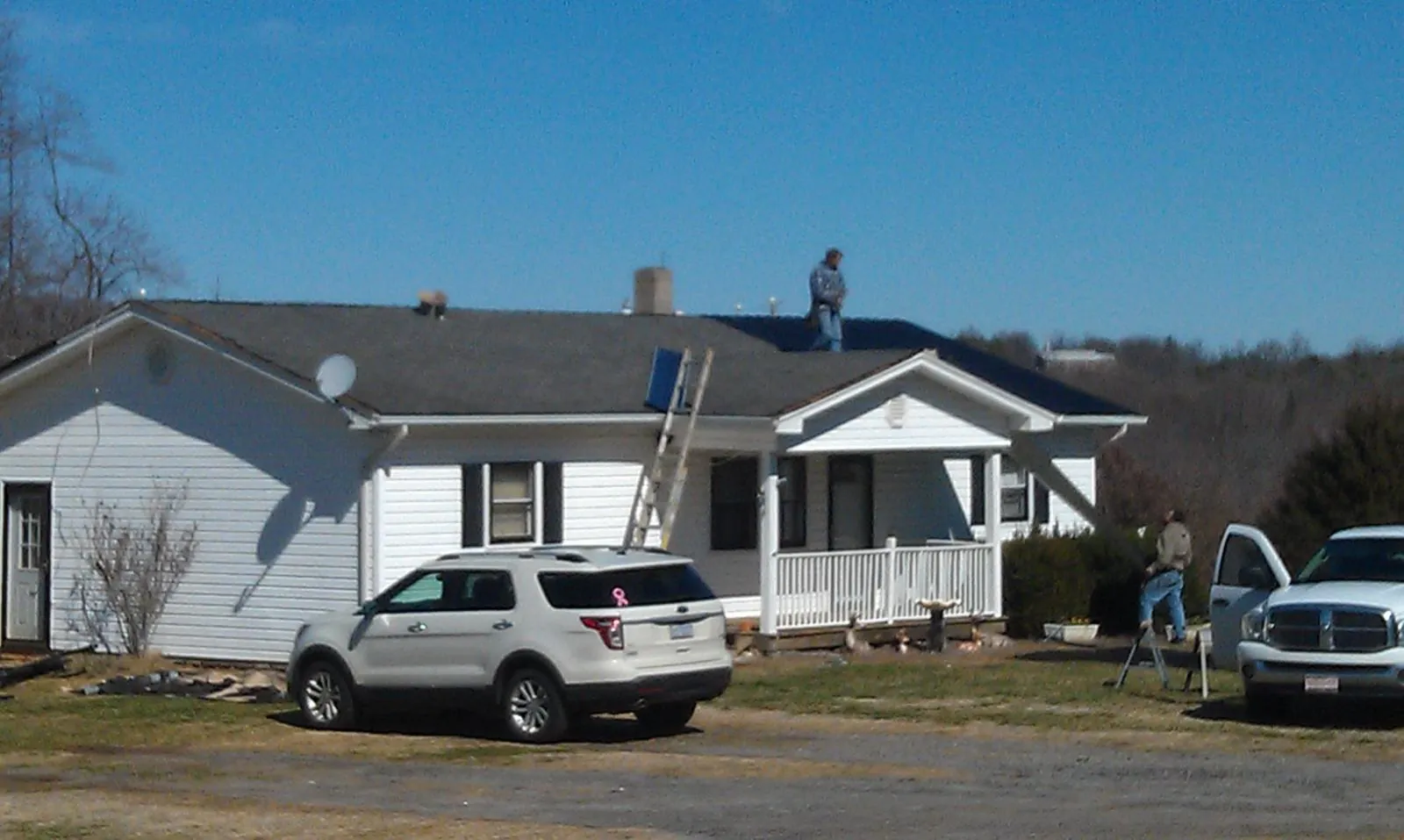 Roofers stripping shingles from a white ranch house roof in Jackson